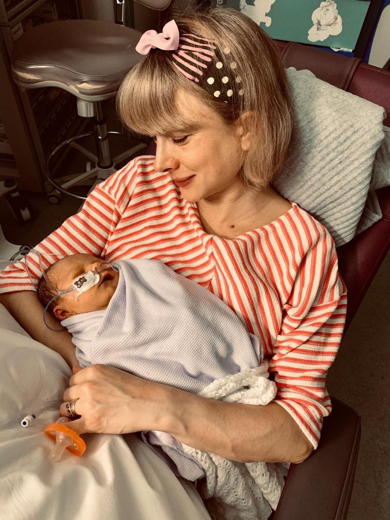 Suzie with a baby in her arms. The baby has a tube going into his nostril.